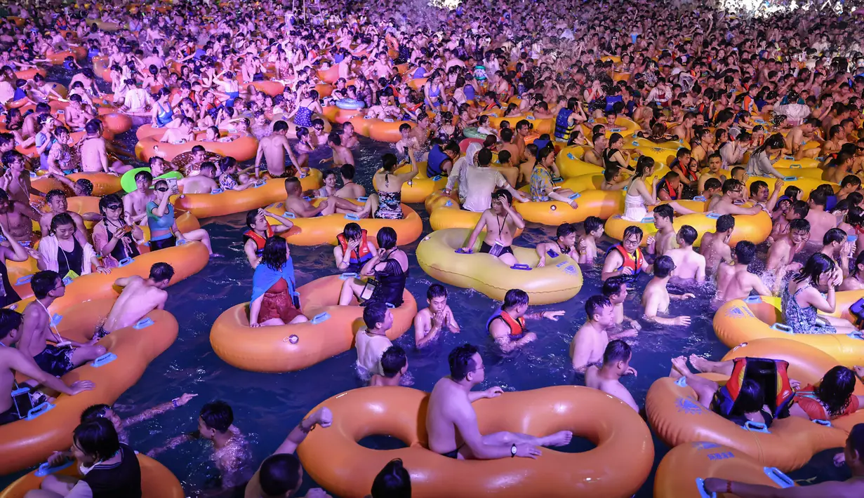 Corona Berlalu, Warga Wuhan Pesta di Kolam: Orang-orang menonton pertunjukan musik sambil bermain air di sebuah taman air atau water park di Wuhan, provinsi Hubei, China, 15 Agustus 2020. Mereka berpesta saat Wuhan kembali ke kehidupan normal setelah sempat terdampak parah oleh COVID-19. (STR/AFP)