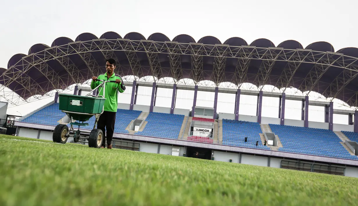 Pekerja sedang melakukan pemupukan rumput di Stadion Indomilk Arena, Tangerang pada Rabu (25/08/2021) sore WIB. Hal tersebut merupakan salah satu bentuk perawatan dan persiapan stadion untuk menyambut kompetisi BRI Liga 1 yang akan segera bergulir. (Foto: Bola.com/Bagaskara Lazuardi)