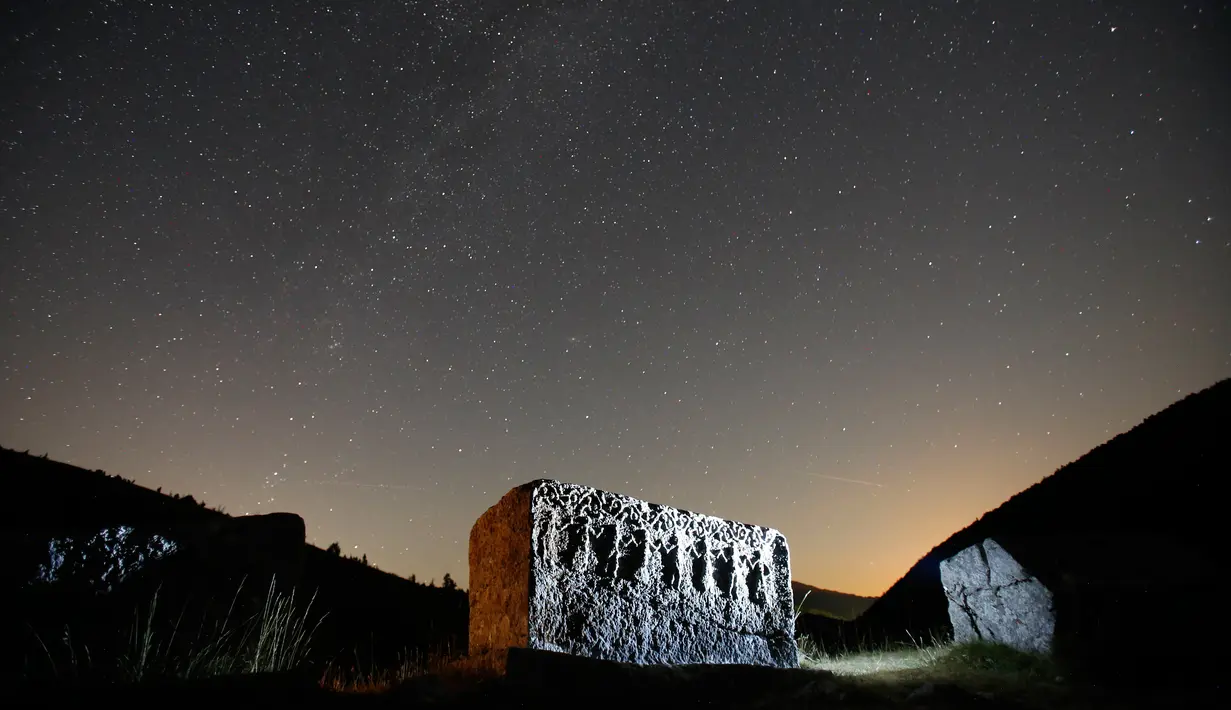 Bintang dan garis-garis meteor (dekat garis cakrawala) terlihat di balik batu nisan abad pertengahan di gunung Bjelasniaca, Bosnia (11/8). Fenomena hujan meteor Perseid terjadi setiap tahun mulai dari Juli sampai akhir Agustus. (AP Photo/Amel Emric)