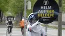 Seorang pesepeda diperlihatkan peringatan untuk mengenakan helm oleh siswa berkostum astronaut, di Ring Street, Wina, Austria, Rabu (5/5/2021). Delapan siswa Wina berpartisipasi dalam acara tersebut untuk mengingatkan pengendara sepeda mengenakannya helm demi keamanan mereka. (JOE KLAMAR/AFP)