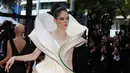 Sang model berjalan di karpet merah dengan gaun putih Cheney Chan yang mencolok dan pahatan yang dibuat agar terlihat seperti kelopak bunga yang lembut. (Valery HACHE / AFP)