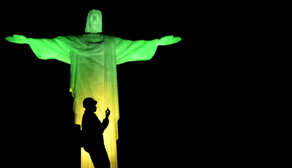 Dekorasi lighting patung Jesus oleh seniman Prancis Gaspare Di Caro beberapa menit sebelum pembukaan Olimpade Rio 2016 di Rio de Janeiro.(AFP/Jeff Pachoud)