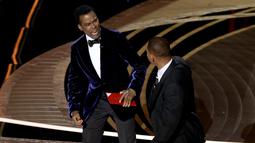 Will Smith (kanan) memukul presenter Chris Rock di atas panggung Piala Oscar 2022 saat penghargaan untuk film dokumenter terbaik di Dolby Theatre, Minggu (27/3/2022). Will Smith merasa lawakan sang komedian terkait istrinya, Jada Pinkett Smith keterlaluan. (Neilson Barnard/Getty Images/AFP)