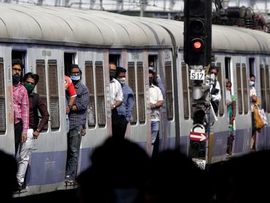 Orang-orang bepergian dengan kereta api lokal, banyak yang mengenakan masker di bawah hidung, di Mumbai, India, pada 12 Januari 2022. Wajib pakai masker di India. Dan polisi turun ke jalan, mengawasi orang-orang untuk memastikan mereka ada di tempat. (AP Photo/Rajanish kakade)
