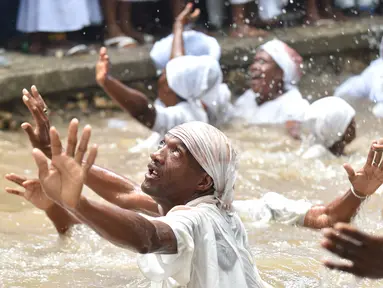 Pengikut Voodoo Haiti mandi di kolam suci selama upacara voodoo di Souvenance, Haiti (4/1). Sejumlah ritual digelar para pengikuti Voodoo Haiti ini selam akhir pekan perayaan Paskah. (AFP/Hector Retamal)