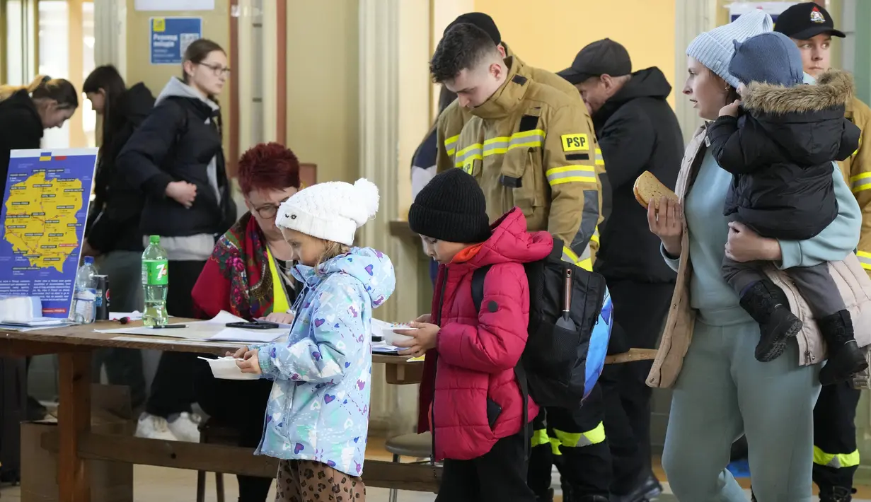 Anak-anak dari Ukraina menerima sup di stasiun kereta api di Przemysl, Polandia tenggara, pada Rabu (23/3/2022). Polandia telah menerima lebih dari 2 juta pengungsi Ukraina sejak invasi Rusia pada 24 Februari lalu. (AP Photo/Sergei Grits)