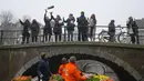 Orang-orang menangkap karangan bunga tulip gratis di Amsterdam, Belanda, Sabtu (15/1/2022). Toko-toko di seluruh Belanda dengan hati-hati dibuka kembali setelah berminggu-minggu penguncian virus corona. (AP Photo/Peter Dejong)