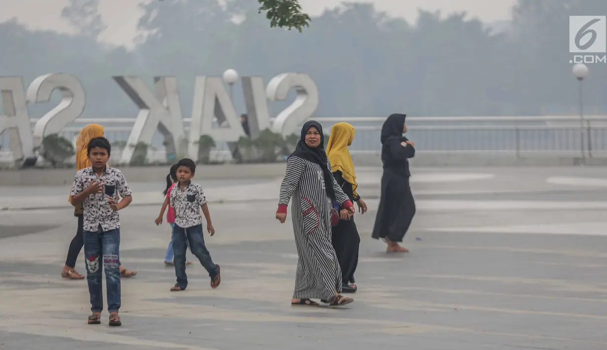 Warga beraktivitas saat asap kebakaran lahan gambut menyelimuti alun-alun Kabupaten Siak, Riau, Kamis (12/9/2019). Asap pekat kebakaran lahan gambut tersebut selain mengganggu kesehatan serta mencemari udara sehingga kualitasnya turun ke status tidak sehat. (Liputan6.com/Faizal Fanani)