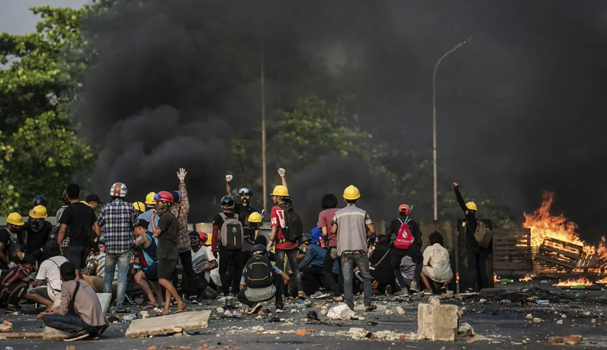 Para pengunjuk rasa berlindung di balik perisai buatan sendiri saat mereka menghadapi polisi selama tindakan keras terhadap demonstrasi menentang kudeta militer di Yangon, Myanmar, 16 Maret 2021. (STR/AFP)