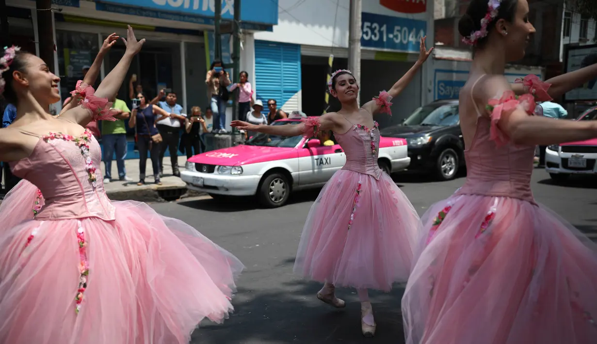 Balerina menampilkan tarian balet saat lampu merah di tengah jalanan Mexico City, 28 Juli 2018. Para balerina dari sanggar Ardentia itu membawakan tarian klasik  untuk menghibur para pengendara di persimpangan yang macet. (AP/Emilio Espejel)