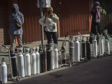 Warga mengantre untuk mengisi ulang tabung oksigen di stasiun pengisian di kota Surabaya, Kamis (15/7/2021). Di Surabaya, masih banyak permintaan isi ulang oksigen, baik tabung kecil 0,5–1 meter kubik hingga ukuran besar 6–7 meter kubik. (Juni Kriswanto / AFP)