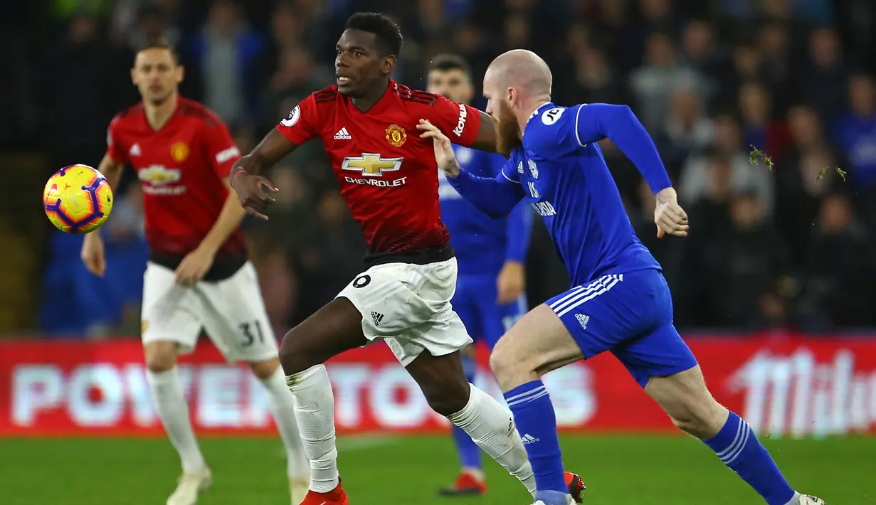 Gelandang Manchester United, Paul Pogba, berusaha melewati gelandang Cardiff, Aron Gunnarsson, pada laga Premier League di Stadion Cardiff City, Wales, Sabtu (22/12). Cardiff kalah 1-5 dari MU. (AFP/Geoff Caddick)