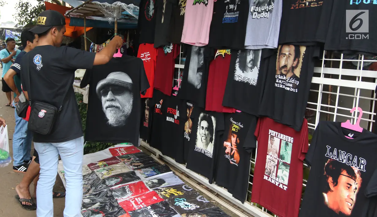 Penggemar Iwan Fals memilih kaos yang dijajakan di luar lokasi Konser Situs Budaya, kawasan Depok, Jawa Barat, Sabtu (3/3). Konser dengan konsep sosial ini merupakan rangkaian dari konser sebelumnya yang sudah digelar. (Liputan6.com/Arya Manggala)