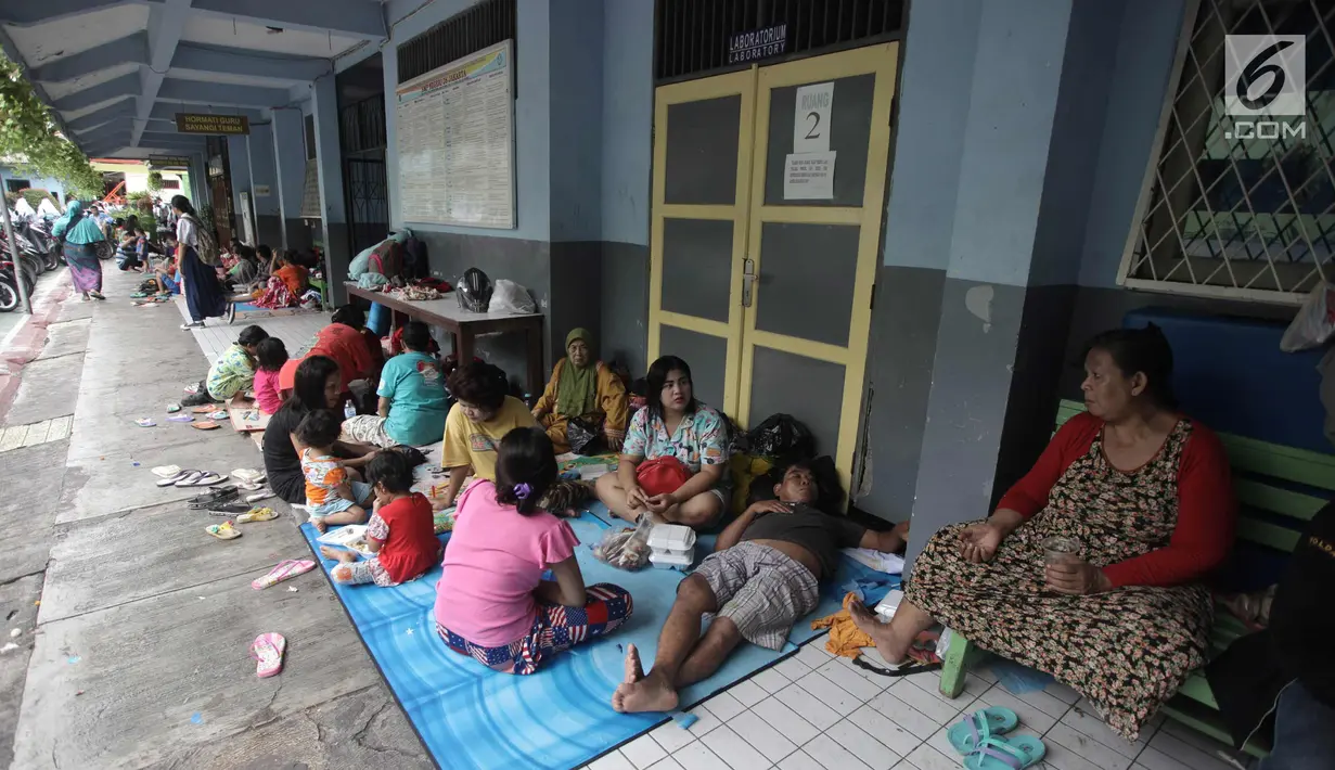 Warga beristirahat di Gedung SMP Negeri 26, Jalan Kebon Pala, Kampung Melayu, Jatinegara, Jakarta Timur, Selasa (6/2). Sebanyak 42 KK mengungsi di tempat tersebut akibat rumahnya terendam banjir. (Liputan6.com/Arya Manggala)
