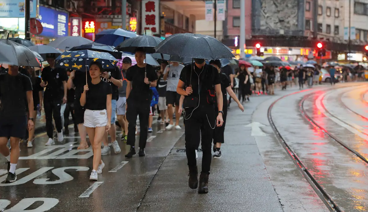 Pengunjuk rasa membawa payung saat menuju Victoria Park, Hong Kong, Minggu (18/8/2019). Puluhan ribu massa pro-demokrasi membawa payung saat hujan mengguyur Victoria Park dan sekitarnya. (AP Photo/Kin Cheung)