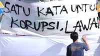 Warga menandatangani spanduk dukungan anti korupsi yang dibentangkan saat Hari Bebas Kendaraan di kawasan Bundaran HI, Jakarta, Minggu (10/12). Aksi dilakukan untuk memperingati Hari Anti-Korupsi Sedunia, 9 Desember. (Liputan6.com/Helmi Fithriansyah)