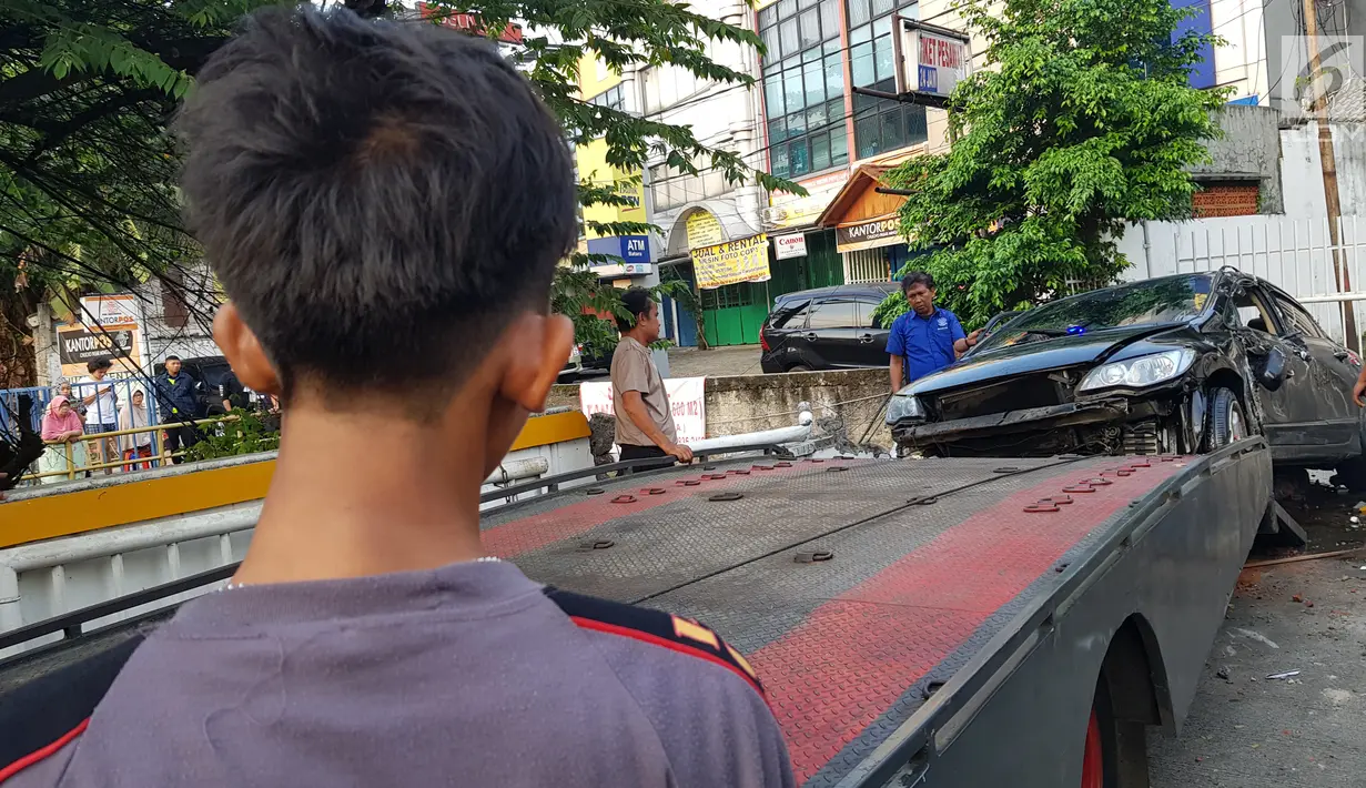 Petugas berusaha mengevakuasi mobil yang terguling di kawasan Pasar Minggu, Jakarta Selatan, Sabtu (8/6/2019) pagi. Mobil yang nyaris tercebur sungai itu dikendarai seorang pemuda yang nekat melakukan aksi kebut-kebutan saat jalanan ibu kota lengang. (Liputan6.com/Herman Zakharia)