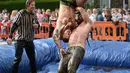 Pegulat membanting lawannya saat mengikuti World Gravy Wrestling Championships ke-10 di Rose 'n' Bowl Pub di Inggris (28/8). Pertandingan gulat ini cukup unik, karena digelar di sebuah kolam selam dua menit. (AFP Photo/Oli Scarff)