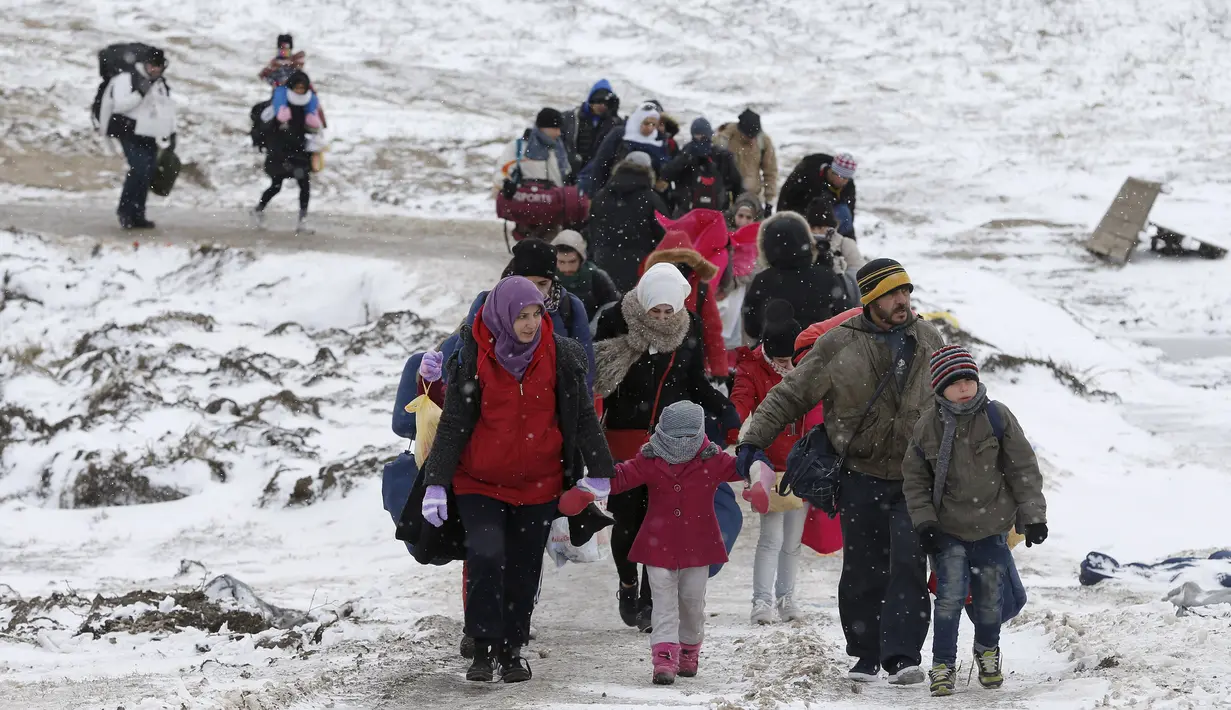 Sejumlah keluarga berjalan melewati salju tebal setelah melintasi perbatasan Macedonia di dekat desa Miratovac, Serbia, (18/1/2016). (REUTERS/Marko Djurica)