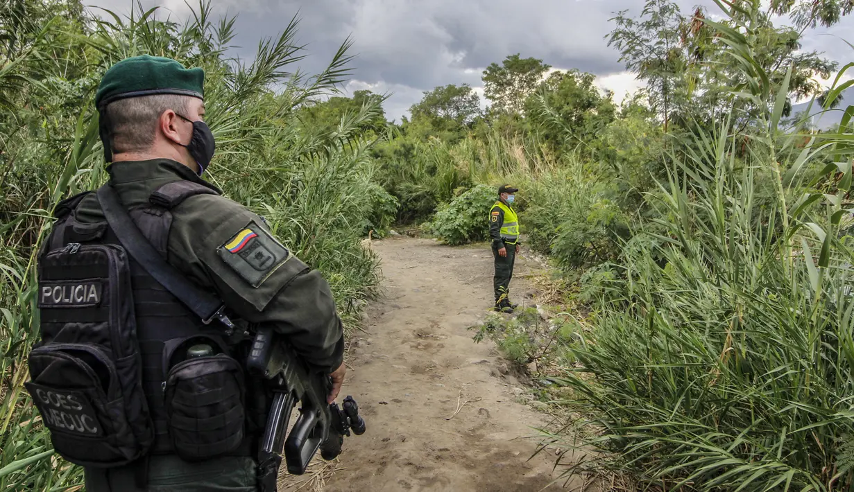 Petugas polisi Kolombia berjaga di "trochas" - jalur ilegal di perbatasan antara Kolombia dan Venezuela,  dekat jembatan internasional Simon Bolivar, di Cucuta, Kolombia (14/10/2020). (AFP/Schneyder Mendoza)