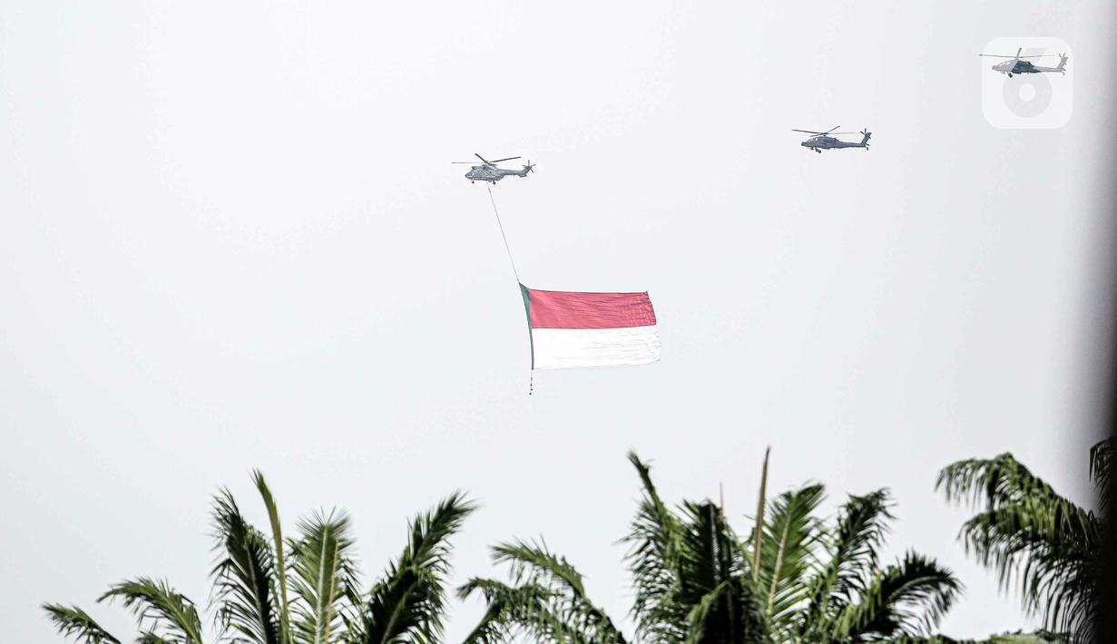 Helikopter TNI AU mengibarkan bendera Merah Putih raksasa di kawasan Gedung DPR RI, Jakarta, Selasa (5/10/2021). TNI AU mengerahkan enam helikopter yang membawa bendera Merah Putih serta bendera Trimatra raksasa. (Liputan6.com/Faizal Fanani)