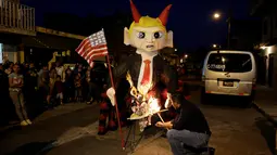 Seorang pria menyiapkan pembakaran pinata karakter Donald Trump saat perayaan tradisional, Pembakaran Iblis di Guatemala City, Guatemala (7/12). Biasanya perayaan ini digelar untuk menyambut natal di daerah Amerika Selatan. (Reuters/Luis Echeverria)