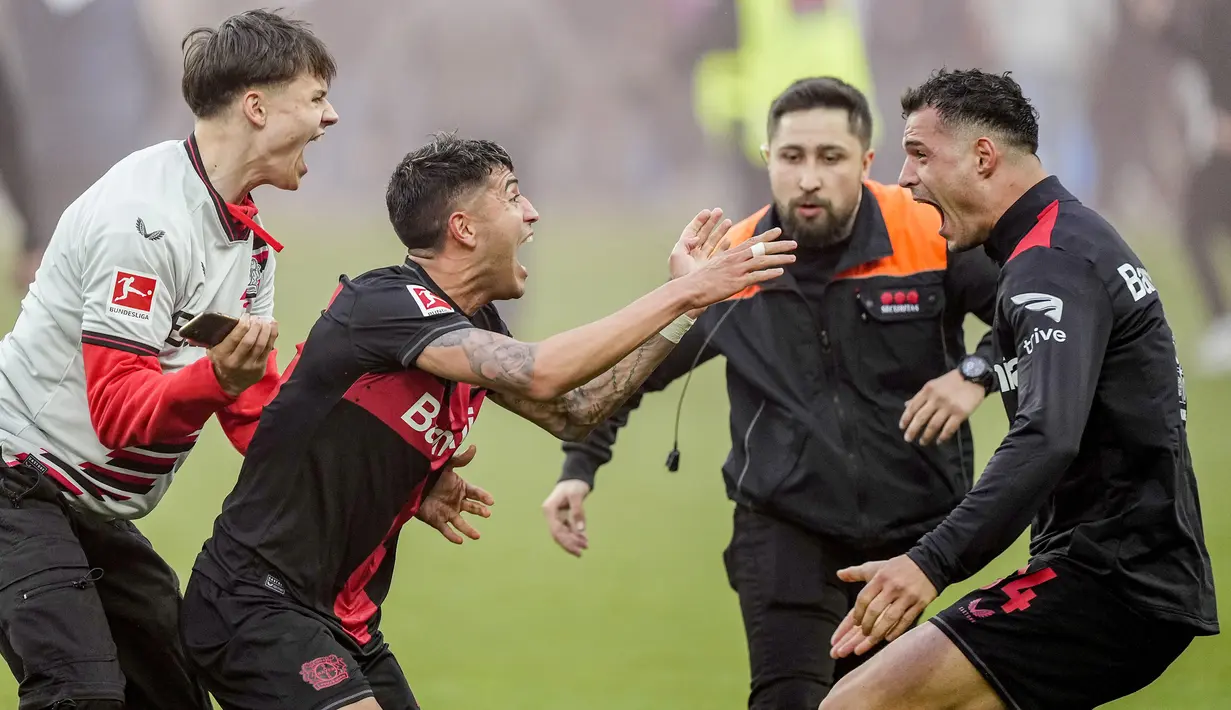 Seorang suporter ikut melakukan selebrasi bersama para pemain Bayer Leverkusen saat memastikan gelar juara Liga Jerman 2023/2024 setelah mengalahkan Werder Bremen di BayArena, Leverkusen, Jerman, Senin (15/04/2024) WIB. (AP Photo/Martin Meissner)