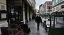 Seorang pria berjalan melewati kafe dan restoran yang tutup di Thessaloniki, Yunani, Selasa (16/11/2021). Pemilik restoran, kafe, dan bar melakukan pemogokan selama 24 jam, memprotes aturan terkait Covid-19 dan biaya energi yang tinggi. (Sakis MITROLIDIS / AFP)