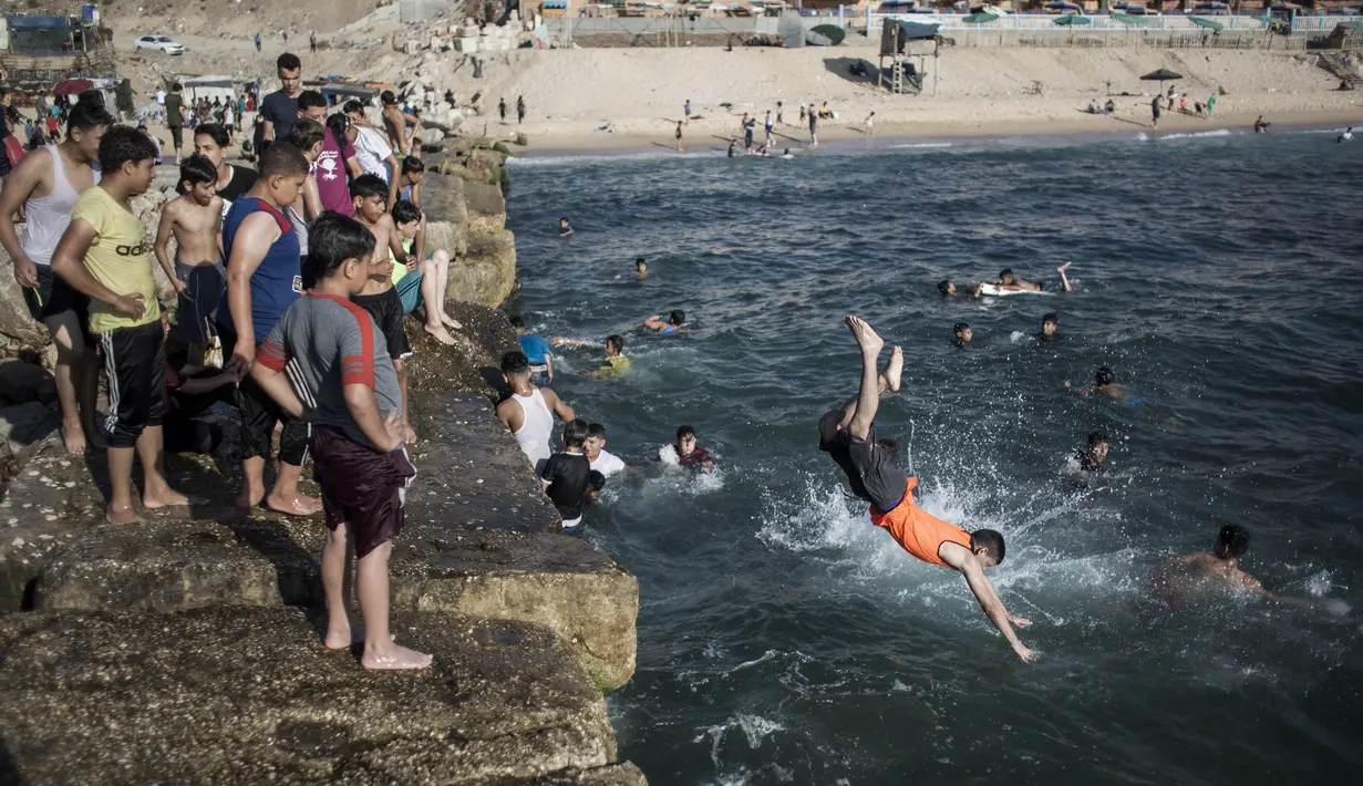 Warga melompat ke laut saat menikmati musim panas yang cerah di pantai Kota Gaza, Palestina, Jumat (3/7/2020). (AP Photo/Khalil Hamra)