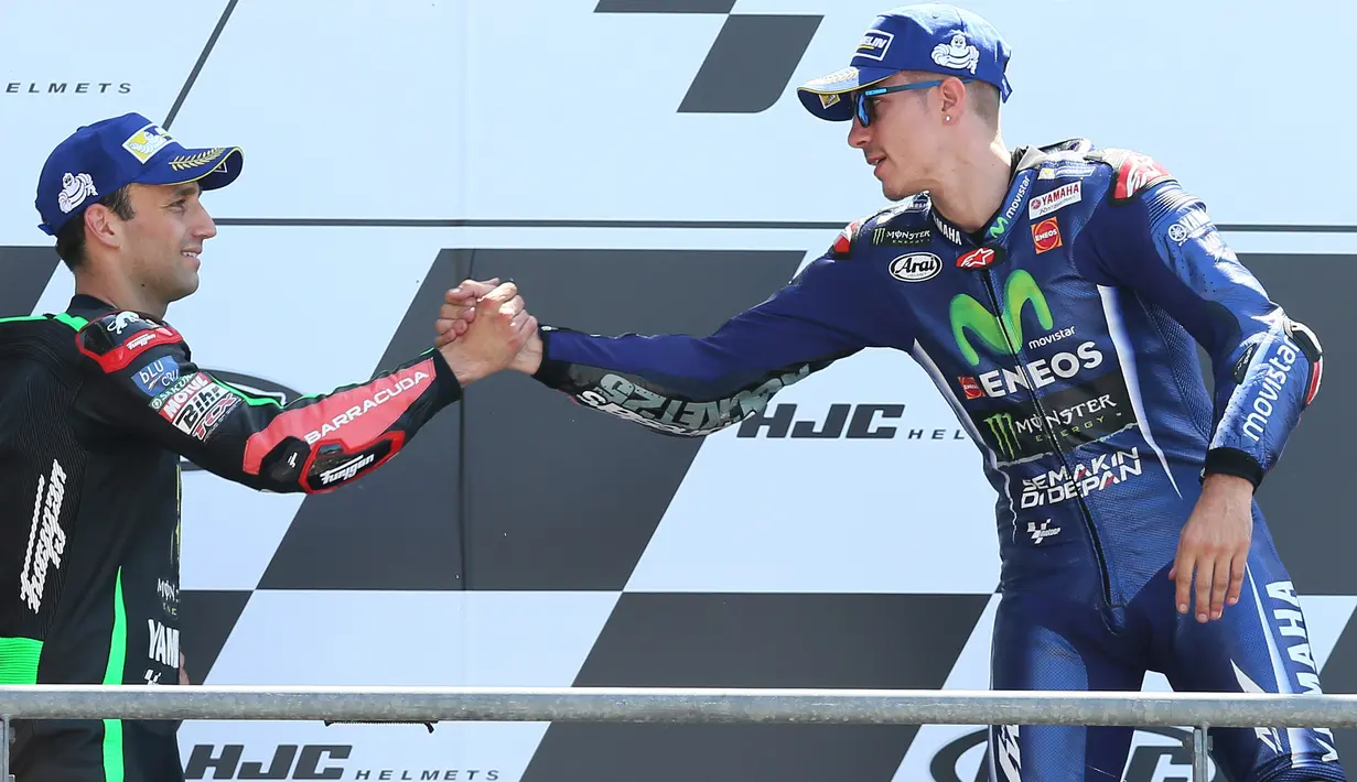 Pembalap Movistar Yamaha dan Tim Yamaha Tech 3, Maverick Vinales dan Johann Zarco saling berjabat tangan di atas podium MotoGP Prancis, Minggu (21/5). Vinales menjuarai MotoGP Prancis disusul Zarco yang menempati posisi kedua. (AP Photo/David Vincent)