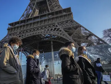 Orang-orang yang memakai masker berjalan melewati Menara Eiffel di Paris, Selasa (21/12/2021). Negara-negara di seluruh Eropa mempertimbangkan pembatasan yang lebih ketat guna membendung gelombang baru infeksi COVID-19 yang didorong oleh varian omicron yang sangat menular. (AP Photo/Michel Euler)