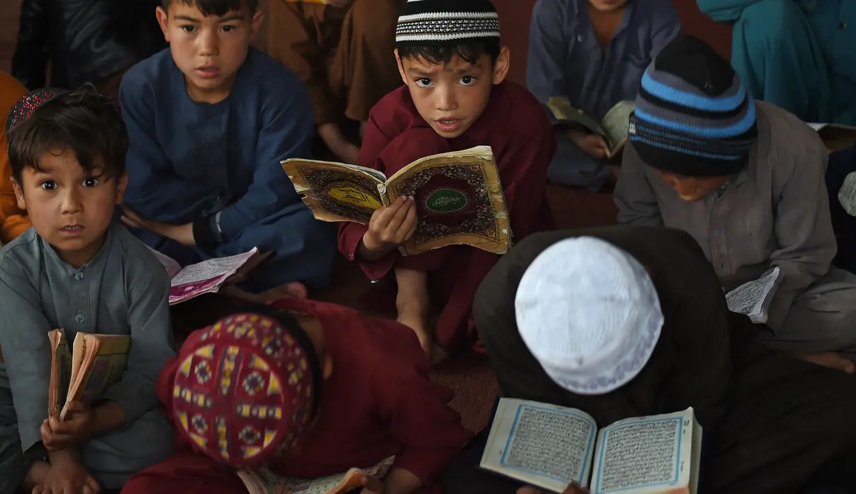 Anak-anak membaca Alquran selama bulan suci Ramadhan di sebuah masjid di pinggiran Kabul, Afghanistan, Selasa (27/4/2021).  Bulan Ramadhan menjadi momen untuk memperbanyak amalan, termasuk ketekunan menjalani tadarus Alquran. (WAKIL KOHSAR / AFP)
