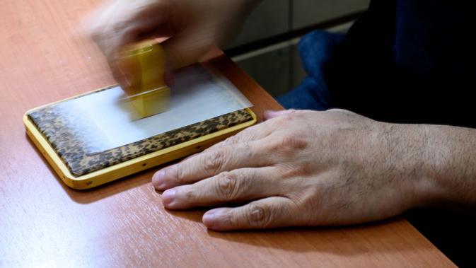 Pembuat stempel tinta tradisional Takahiro Makino, 44, mencap kertas menggunakan hanko di Tokyo pada 9 Oktober 2020. Hanko atau stempel tinta tradisional digunakan untuk menandatangani segala sesuatu mulai dari tanda terima pengiriman hingga sertifikat pernikahan di Jepang. (Philip FONG/AFP)