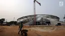 Pekerja melintas di depan pembangunan stadion balap sepeda atau velodrom di Rawamangun, Jakarta, Jumat (3/11). Pembangunan stadion bertaraf internasional ini sudah mencapai 68 persen dan ditarget selesai, Juni 2018. (Liputan6.com/Helmi Fithriansyah)