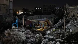 Warga Palestina duduk di tenda yang didirikan di atas reruntuhan bangunan yang hancur dalam serangan udara Israel di Kota Gaza (24/5/2021). Sementara itu, roket dari Gaza merenggut 12 nyawa di Israel, termasuk satu anak dan seorang tentara Israel. (AFP/Mohamed Abed)