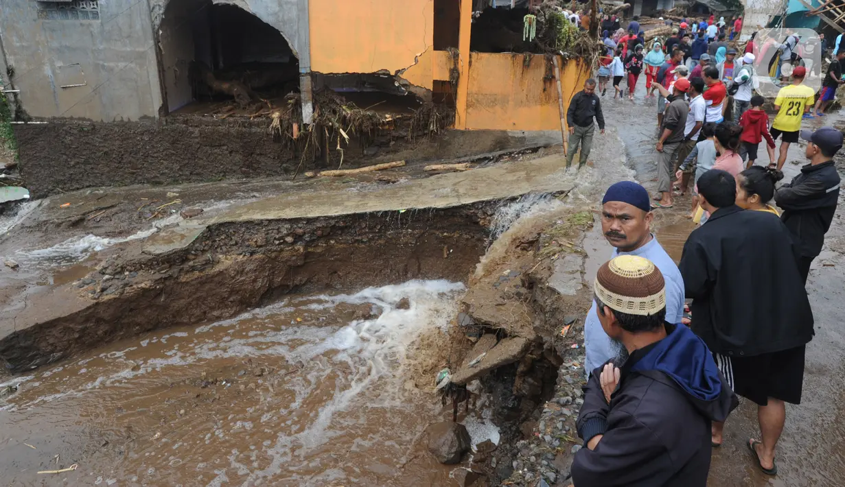 Warga menyaksikan jalan yang tergerus usai banjir bandang melanda Kampung Cibuntu, Desa Pasawahan, Kecamatan Cicurug, Sukabumi, Jawa Barat, Selasa (22/9/2020). Data sementara puluhan bangunan rusak berat, 12 rumah hanyut, dan dua korban hilang masih dicari. (merdeka.com/Arie Basuki)