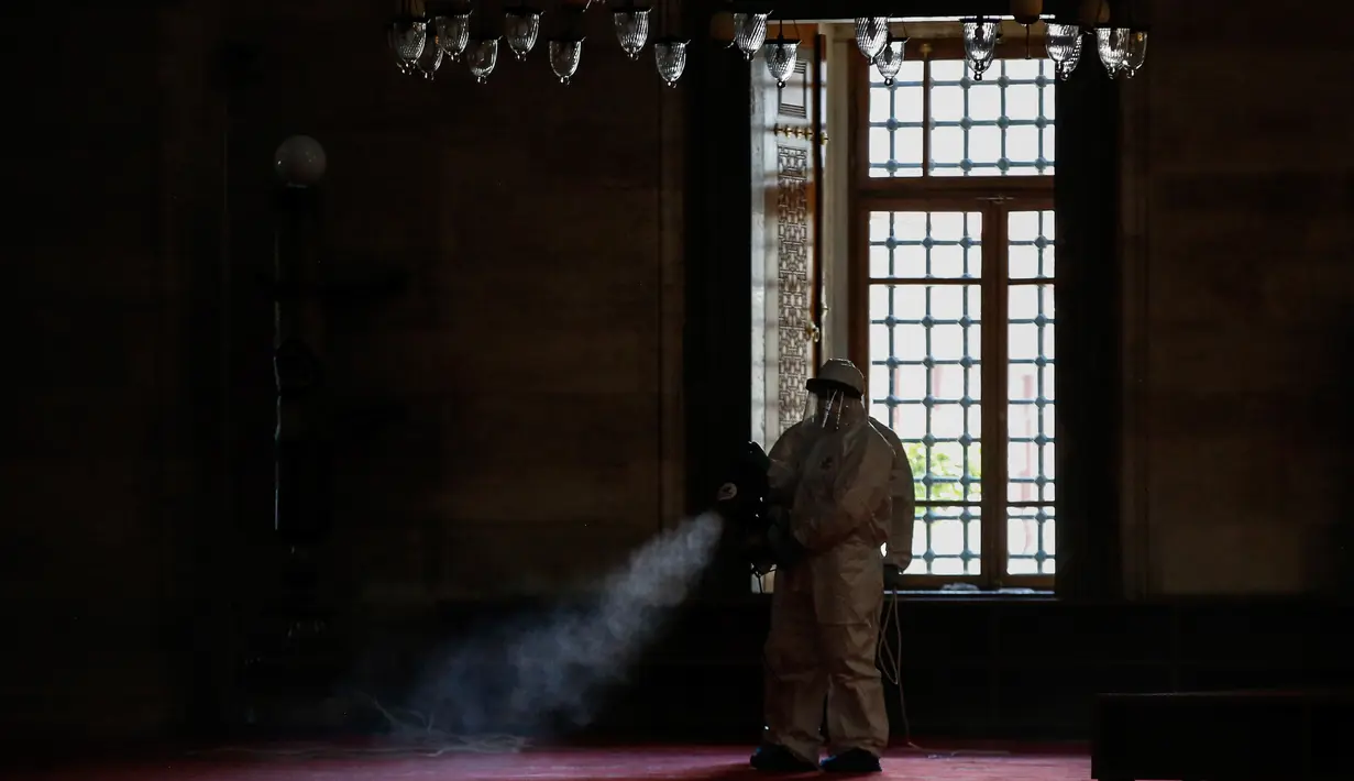 Pekerja mengenakan pakaian pelindung menyemprotkan disinfektan bagian dalam Masjid Suleymaniye yang bersejarah pada hari ketiga Idul Fitri di Istanbul, Selasa (26/5/2020). Beberapa masjid didisinfektan sebelum dibuka kembali pada 29 Mei usai ditutup selama lebih dari enam minggu. (AP/Emrah Gurel)