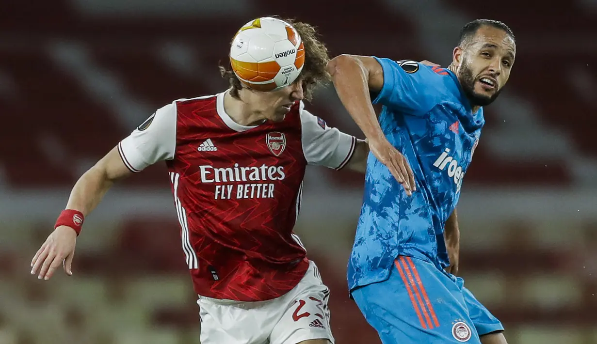 Bek Arsenal, David Luiz (kiri) berduel udara dengan striker Olympiakos, Youssef El-Arabi dalam laga leg kedua babak 16 besar Liga Europa 2020/2021 di Emirates Stadium, London, Kamis (18/3/2021). Arsenal kalah 0-1 dari Olympiakos. (AP/Matt Dunham)