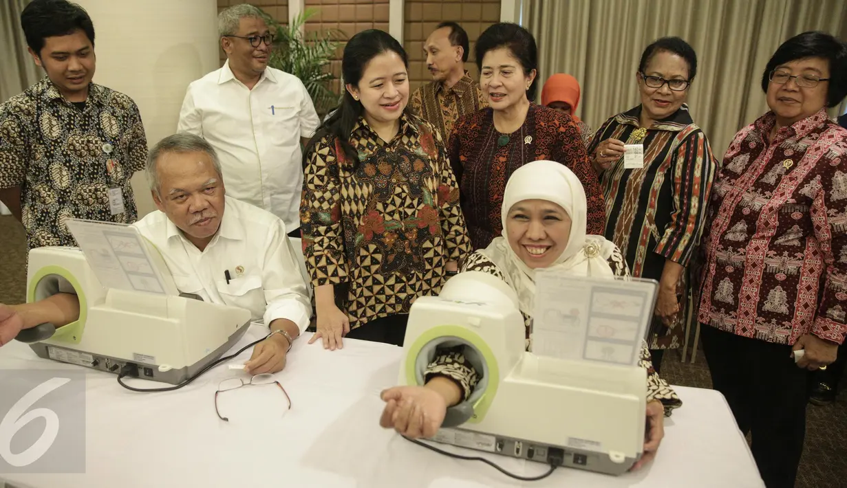 Menteri Sosial Khofifah Indar Parawansa (kanan) dan Menteri Pekerjaan Umum dan Perumahan Rakyat Basuki Hadimuljono mencoba langsung alat pengukur tekanan darah mandiri di kantor Kemenko PMK Jakarta, Rabu (22/2). (Liputan6.com/Faizal Fanani)