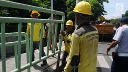 Petugas membongkar pagar pembatas besi di kawasan Pinang Ranti, Jakarta, Senin (11/2). Zebra cross yang berada di samping Tamini Square itu sempat jadi perbincangan lantaran terhalang oleh pagar besi hijau setinggi 1 meter. (Liputan6.com/Herman Zakharia)