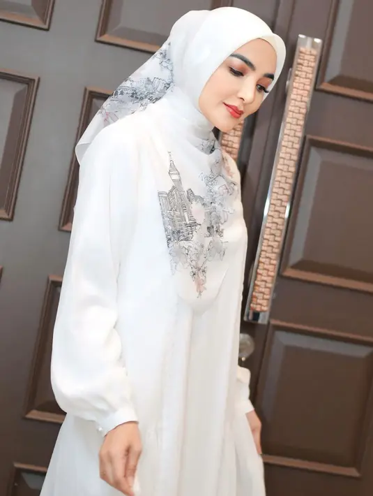 Melengkapi tampilannya dengan kerudung segi empat putih dengan aksen gambar arsitektur. [@ashanty_ash]