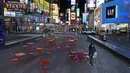 Seorang wanita berjalan melalui Times Square di New York, Senin, (16/3/2020). Gubernur Andrew Cuomo mengatakan restoran dan bar akan pindah ke layanan take-out dan pengiriman saja imbas merebaknya penyebaran Covid-19. (AP Photo/Seth Wenig)