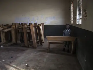 Seorang siswa duduk sendirian di ruang kelas setelah melapor pada hari pertama pembukaan kembali sekolah di Kampala pada 10 Januari 2022. Sekolah-sekolah di Uganda dibuka kembali untuk siswa pada Senin (10/1), mengakhiri penutupan sekolah terlama di dunia akibat pandemi COVID-19. (Badru KATUMBA/AFP)