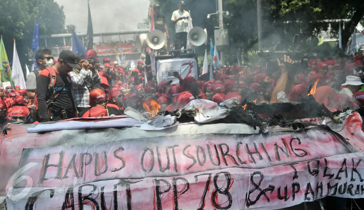 Buruh membakar keranda mayat sebagai simbol kekecewaan terhadap kebijakan pemerintah di Jalan Medan Merdeka Barat, Jakarta, Senin (1/5). (Liputan6.com/Yoppy Renato)