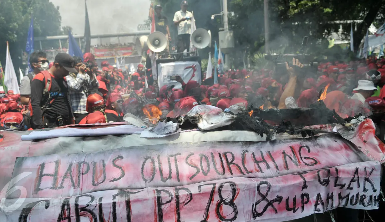 Buruh membakar keranda mayat sebagai simbol kekecewaan terhadap kebijakan pemerintah di Jalan Medan Merdeka Barat, Jakarta, Senin (1/5). (Liputan6.com/Yoppy Renato)