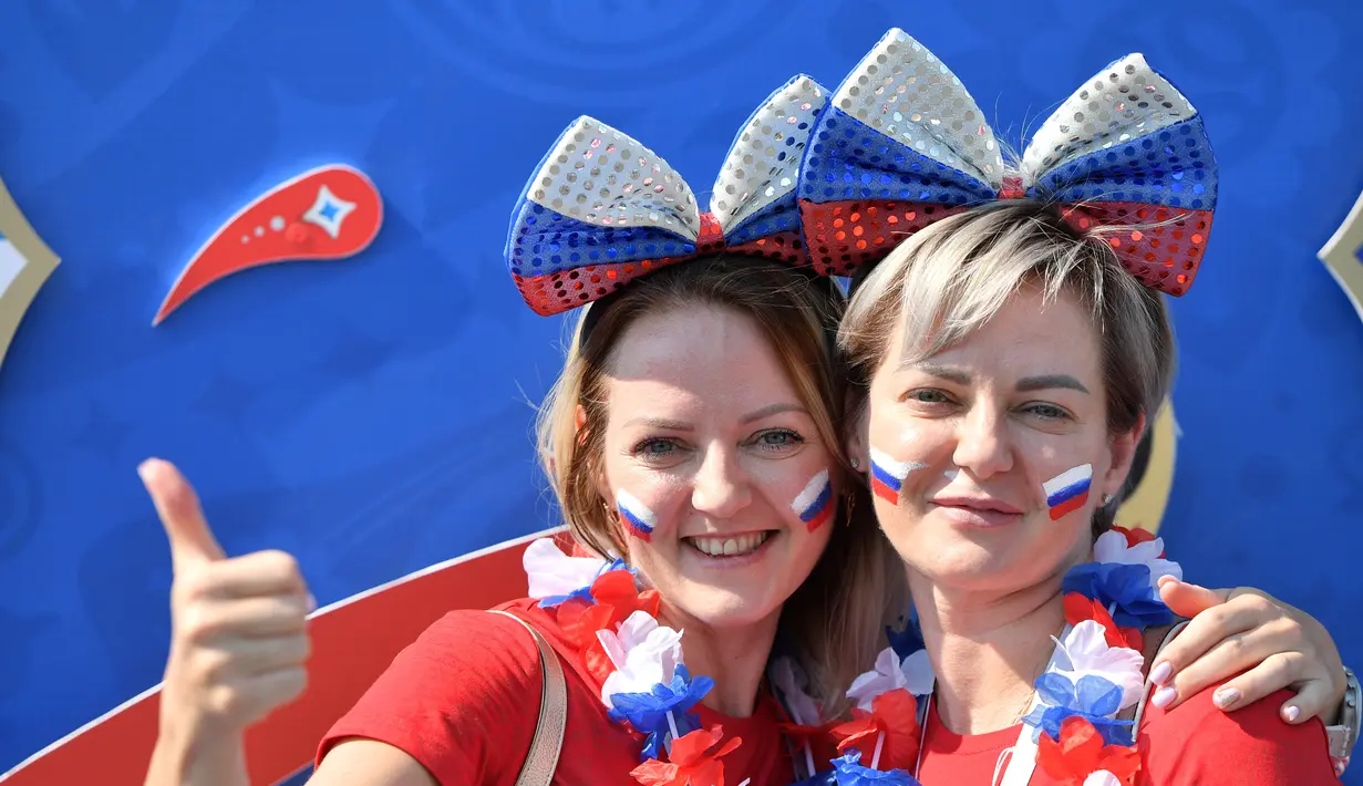 Dua wanita mengecat wajahnya dengan bendera Rusia jelang laga antara Uruguay menghadapi Rusia dalam penyisihan Grup A Piala Dunia 2018 di Samara Arena, Samara, Rusia, Senin (25/6). (EMMANUEL DUNAND/AFP)