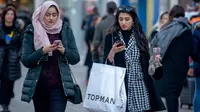 Pembeli memainkan ponsel sambil berjalan membawa kantong belanjaan di Oxford Street, London pada Sabtu (22/12). Menjelang natal, Oxford Street yang merupakan salah satu pusat perbelanjaan di jantung Kota London keramaiannya meningkat. (NIKLAS HALLE'N/AFP)