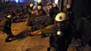 Polisi anti huru hara berlindung dari proyektil yang pengunjuk rasa anti-bailout di Athena, Yunani, Rabu (15/7/2015). Unjuk rasa ini dilakukan menjelang pemungutan suara kesepakatan bailout. (REUTERS /Yiannis Kourtoglou)