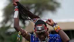 Seorang suku Maasai mengikat rambutnya saat persiapan mengikuti Olimpiade Masai 2016 di dekat perbatasan Kenya-Tanzania (10/12). Suku Maasai adalah kelompok suku asli dari Afrika Timur yang memiliki pola hidup semi-nomaden. (Reuters/Thomas Mukoya)