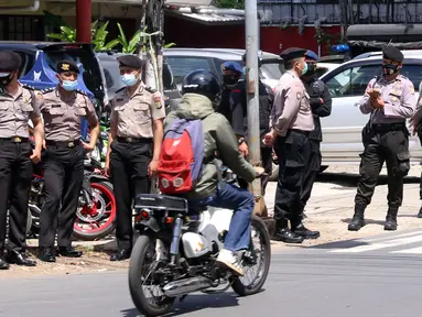 Seorang pengendara sepeda motor melintas dekat sejumlah polisi berjaga di area Pengadilan Negeri Jakarta Selatan, Senin (4/1/2021). Pengamanan ratusan aparat kepolisian dilakukan untuk mengantisipasi pergerakan masa pada saat sidang praperadilan Rizieq Shihab. (Liputan6.com/Angga Yuniar)